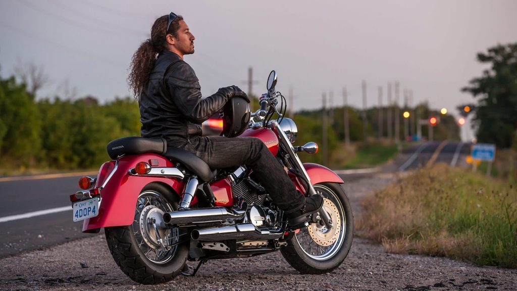 Rider holding helmet and resting on parked Honda Shadow 750 ABS
