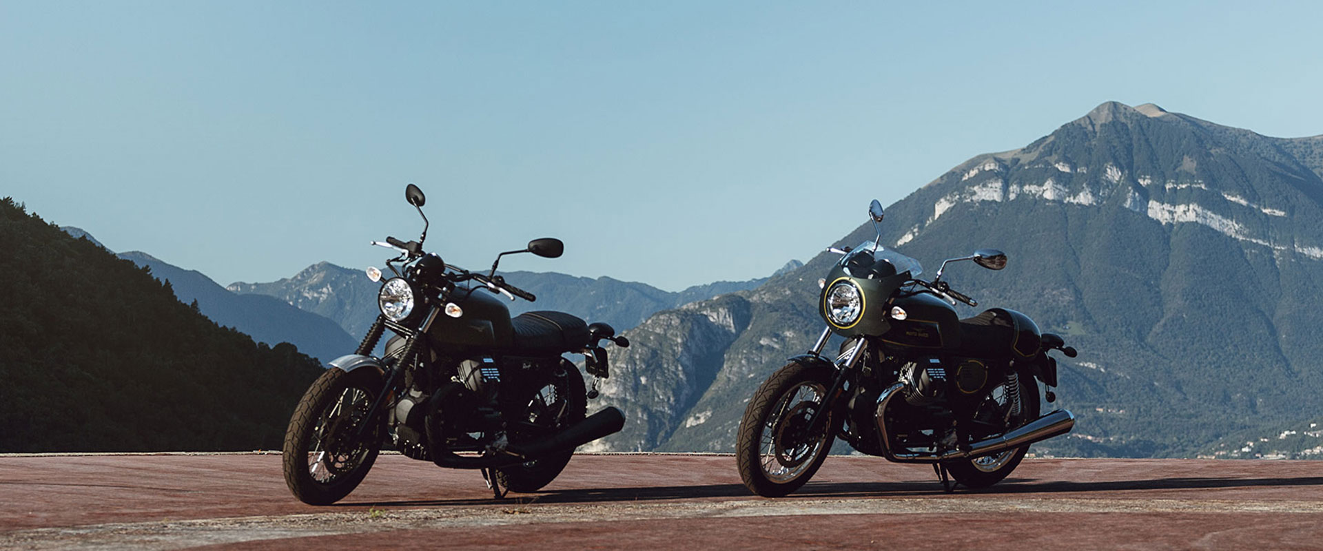 Two Moto Guzzi V7 III motorcycles parked on flats with mountains in background
