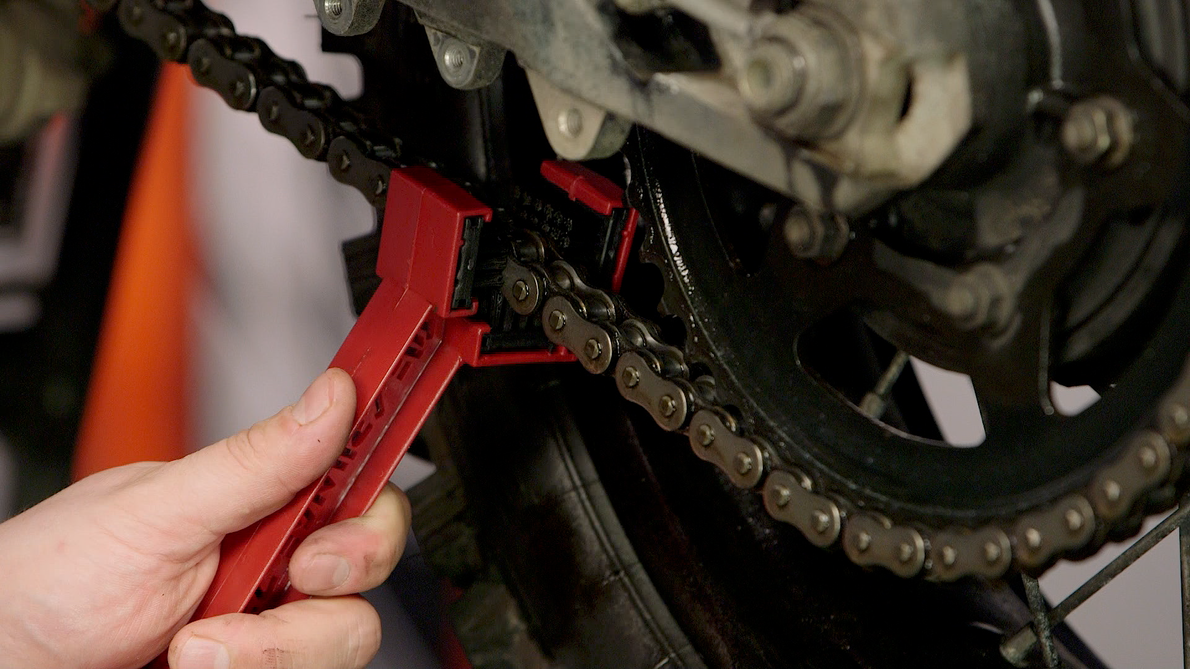Rider cleaning and lubing a motorcycle chain