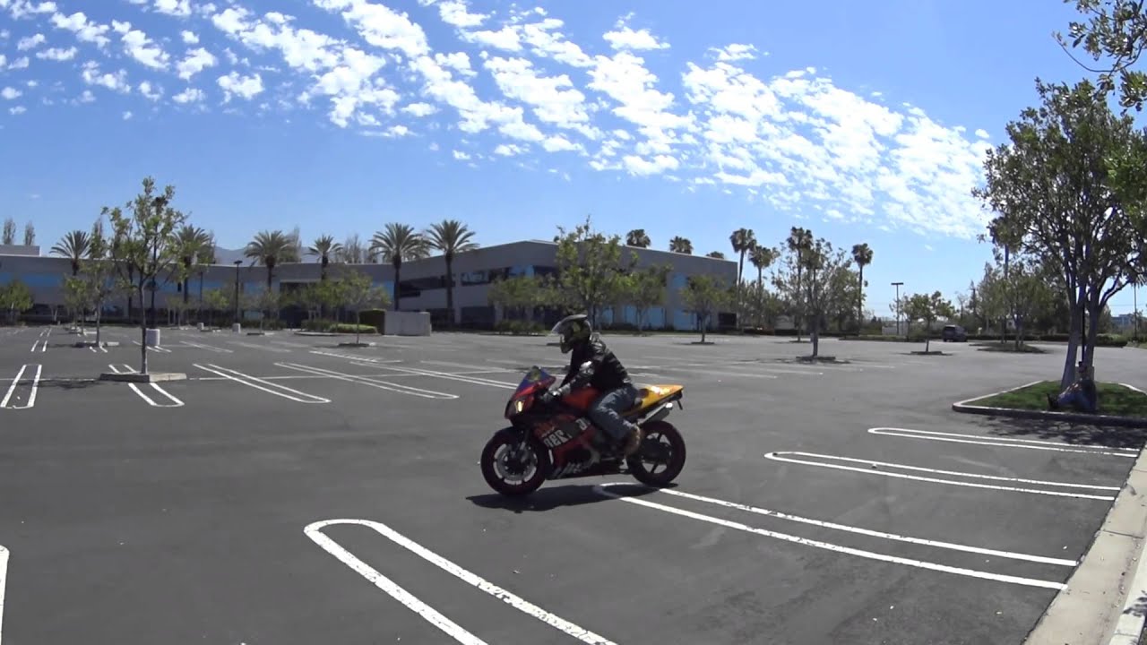 Motorcyclist on bike practicing slow-speed maneuvers in empty parking lot