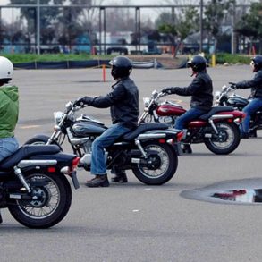 Riders lined up on motorcycles in a parking lot during an MSF class
