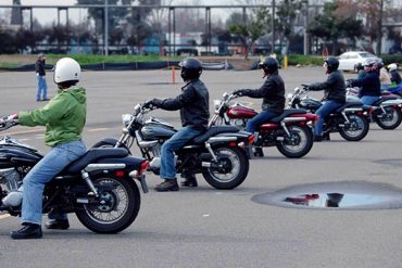 Riders lined up on motorcycles in a parking lot during an MSF class