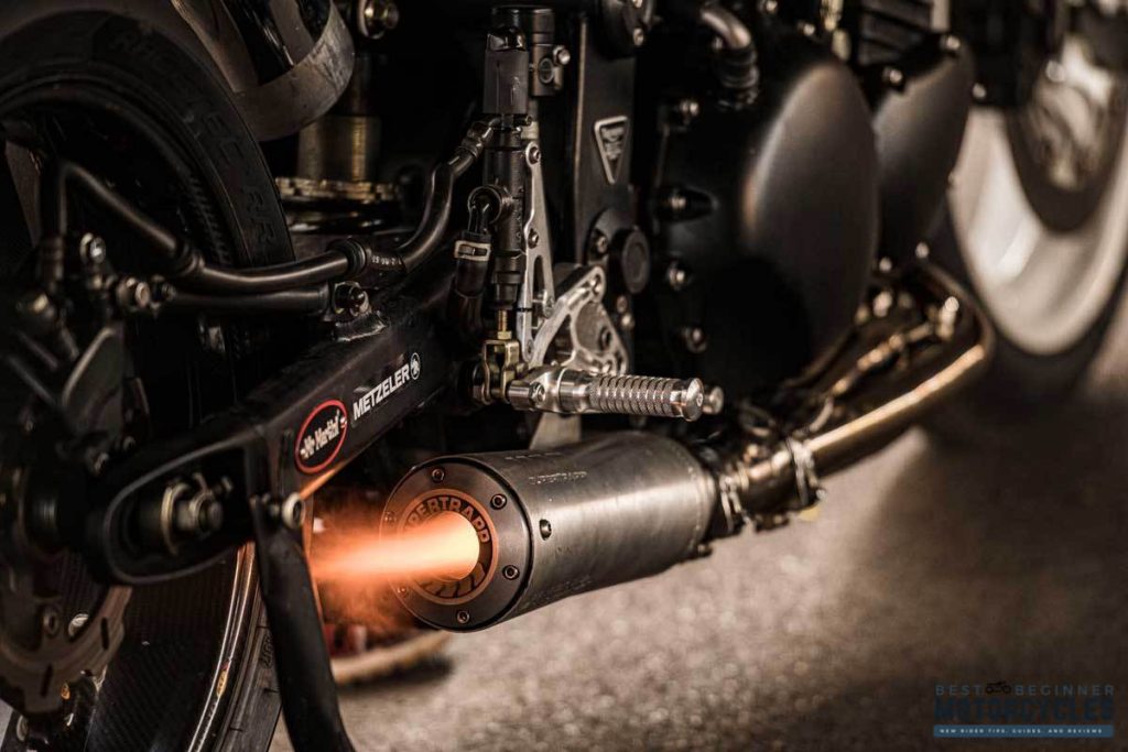 A customised motorcycle with a short exhaust blows flames during high revs in a workshop