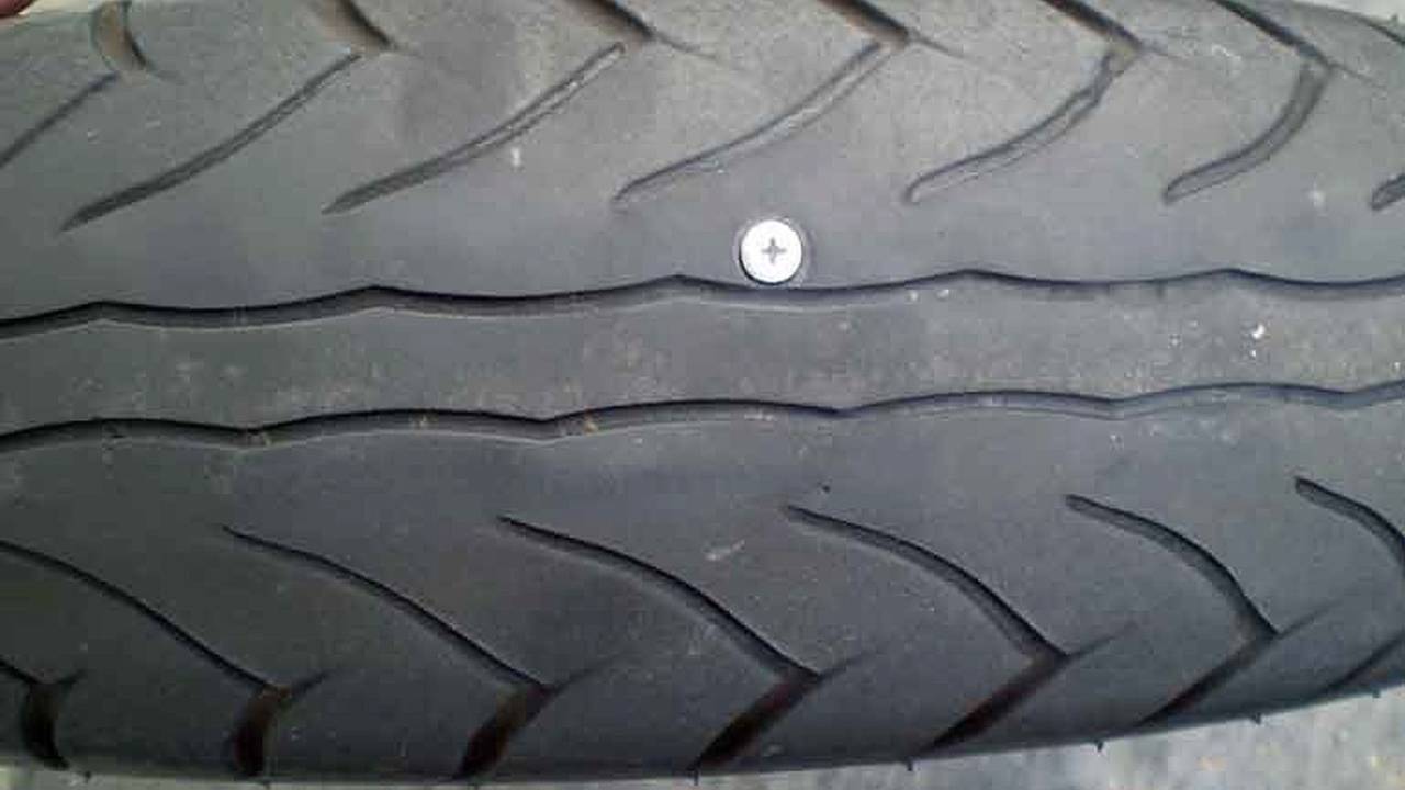 a detailed shot of a motorcycle tyre with a screw embedded in it