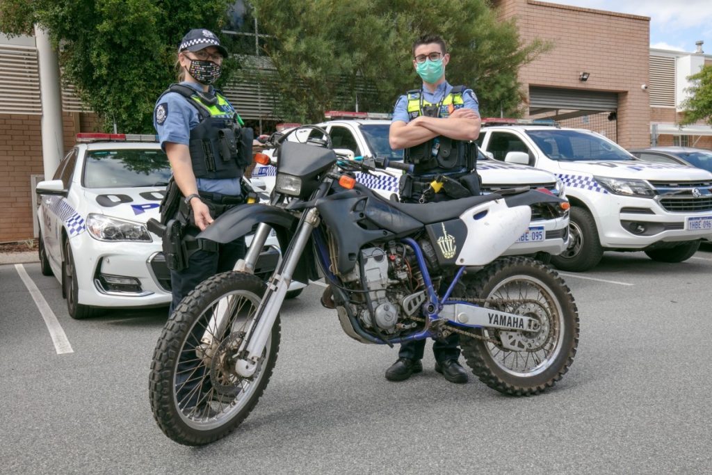 Australian police stand behind an impounded and unregistered motorcycle in Western Australia