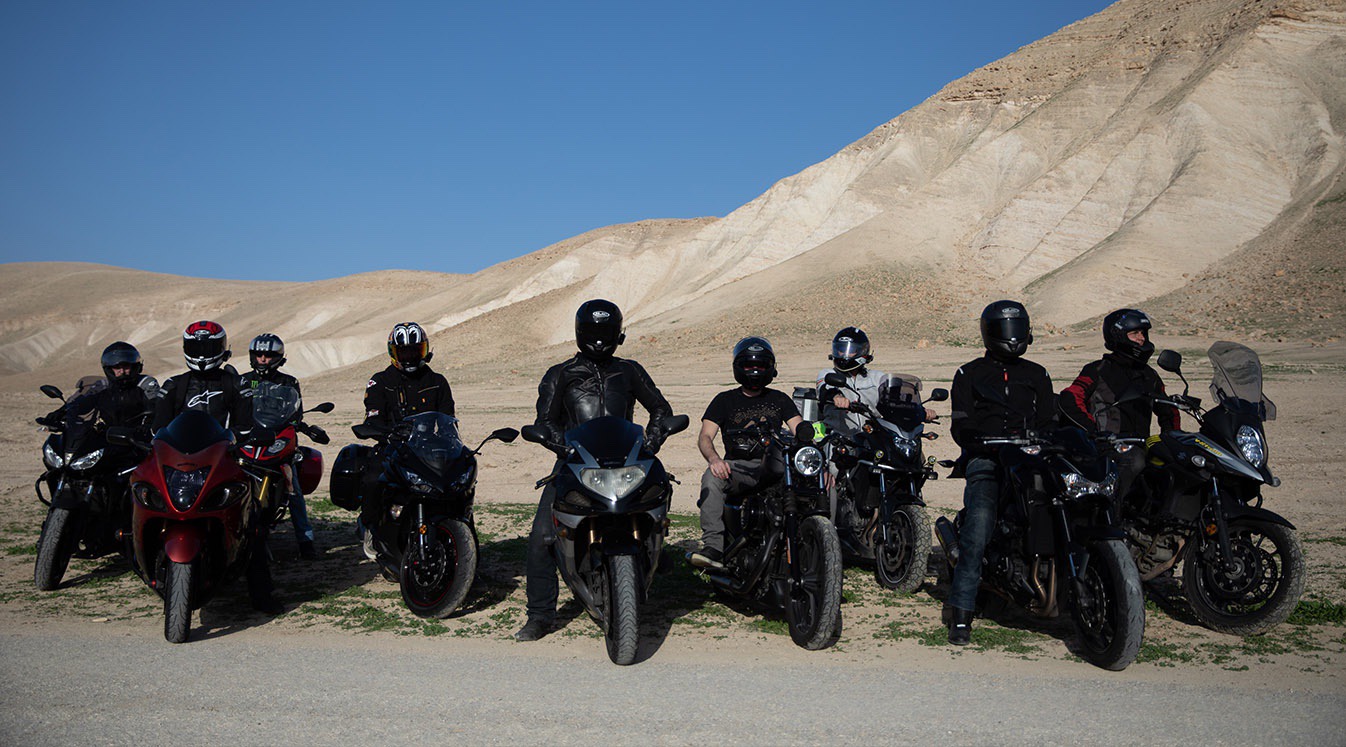 a group of motorcycle riders in the desert stop for a break