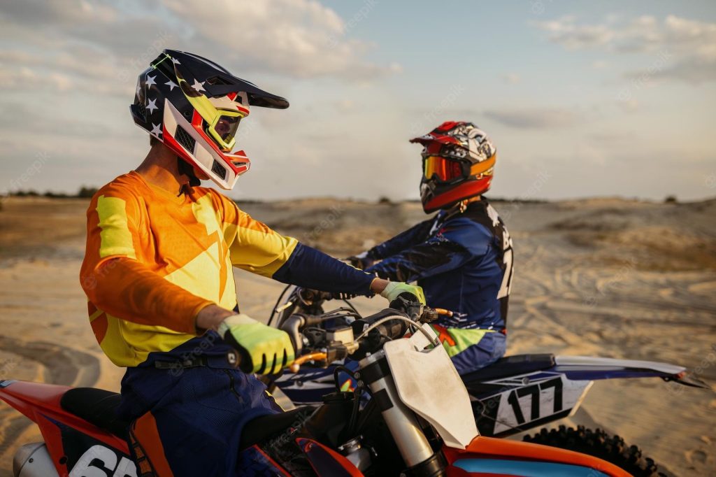Two motocross motorcycle riders stop to swap tips
