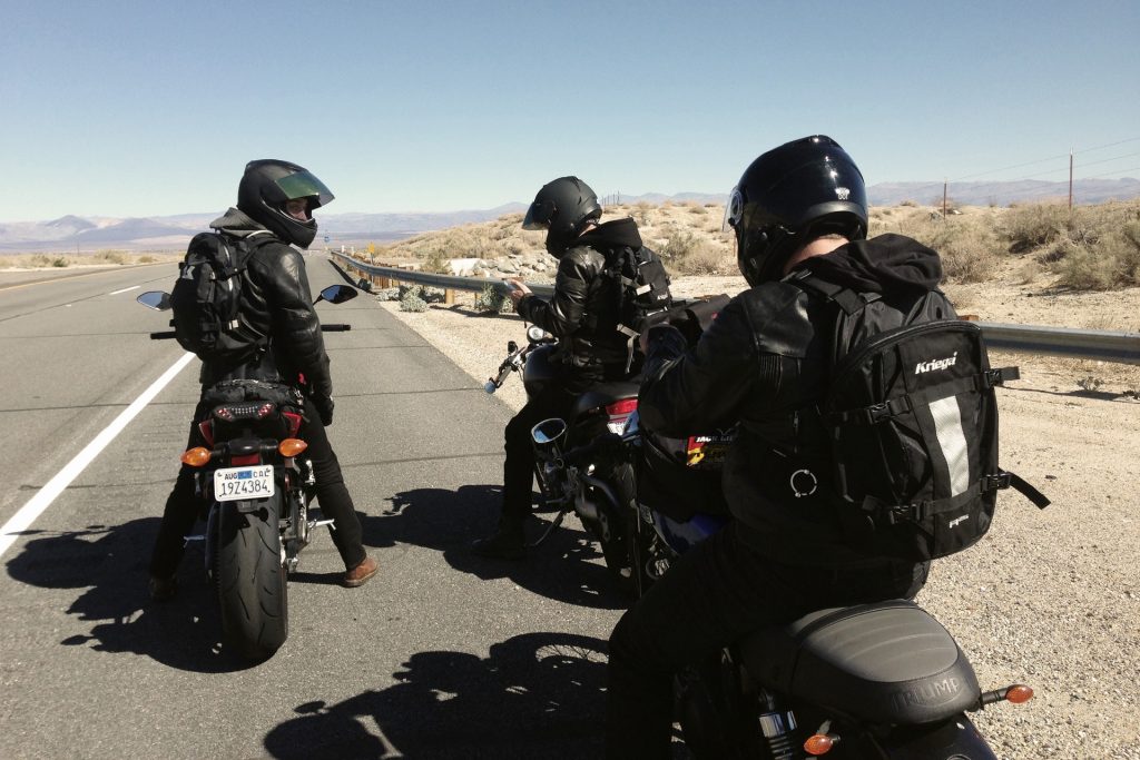 Three motorcyclists stop by the side of the road for a discussion