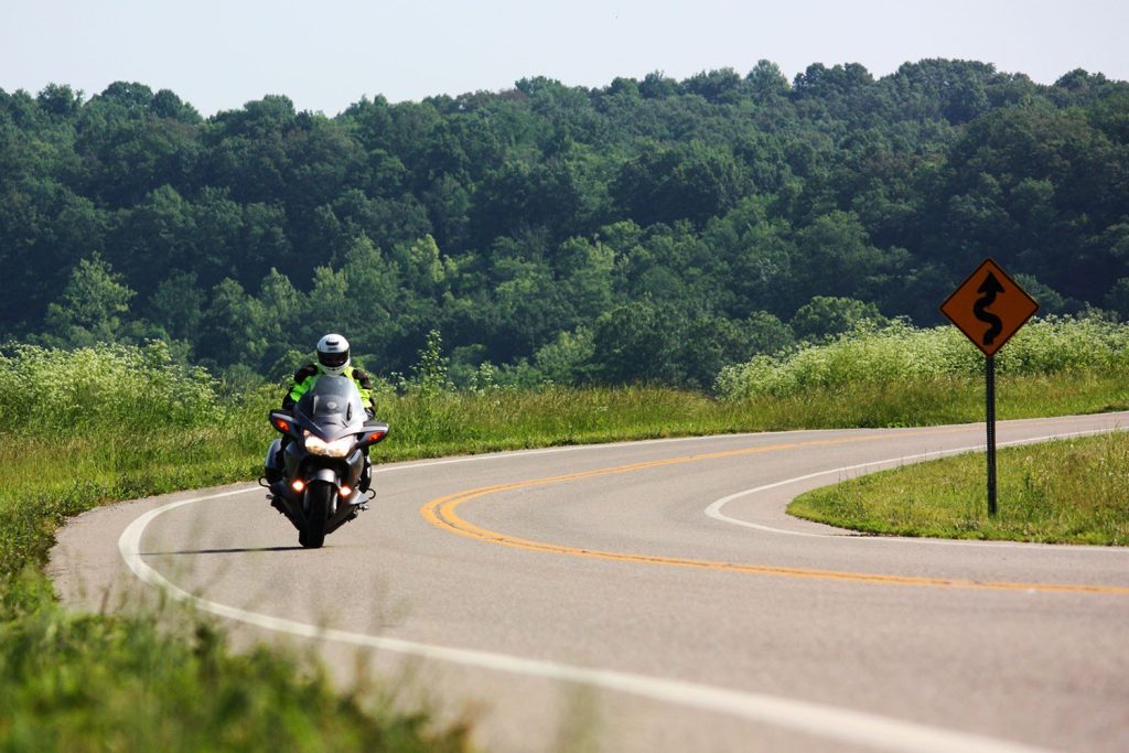 a loan motorcyclist rides on a US road in summer