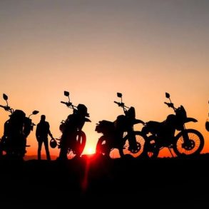 a group of off road motorcyclists stop to watch the sun set