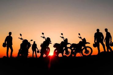 a group of off road motorcyclists stop to watch the sun set