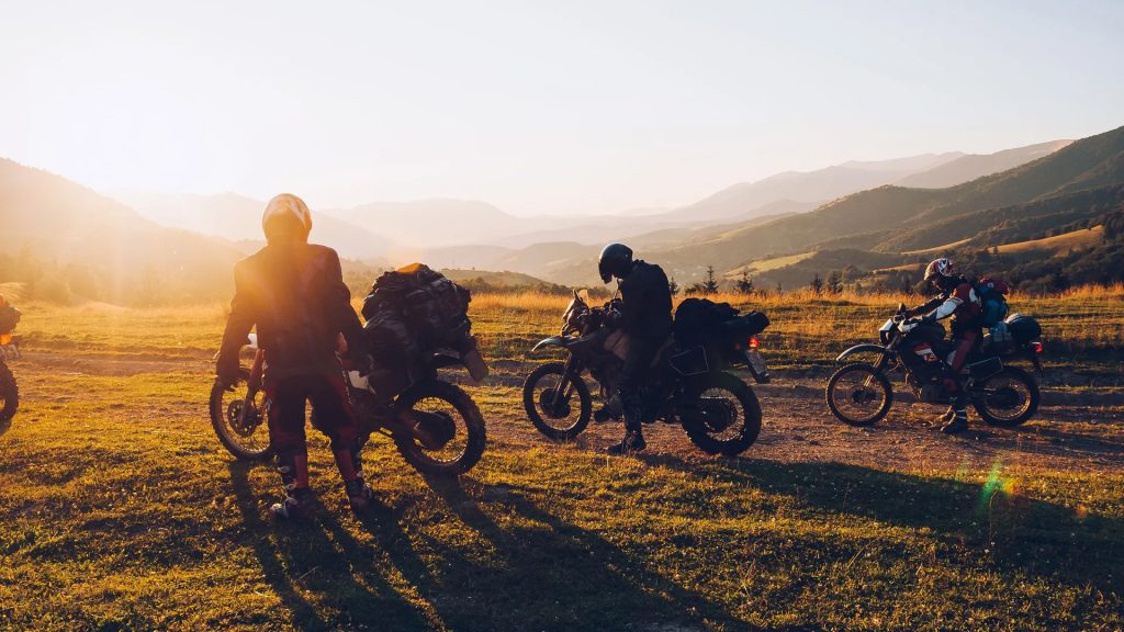 A group of motorcyclists in the country stop to enjoy the sunset and set up camp