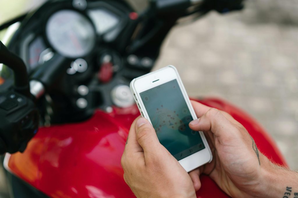 Person accessing online marketplace through smartphone while seated on motorcycle