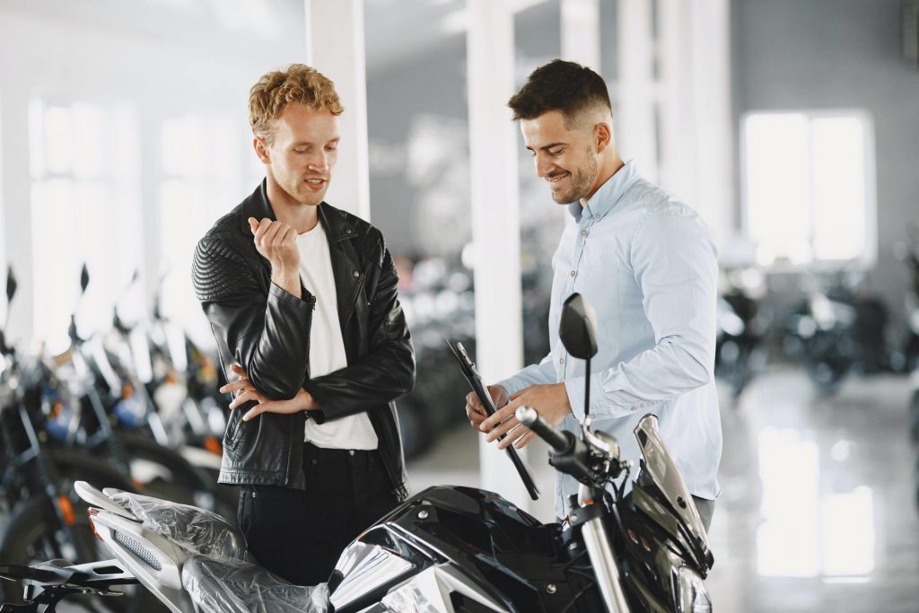 Man in leather jacket talking to staff member at specialty motorcycle dealership