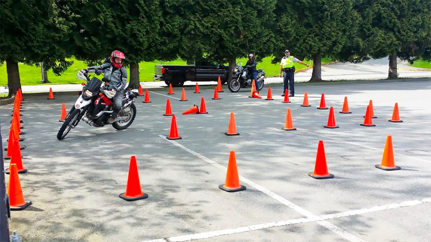 A motorcyclist undergoes training in a car park area