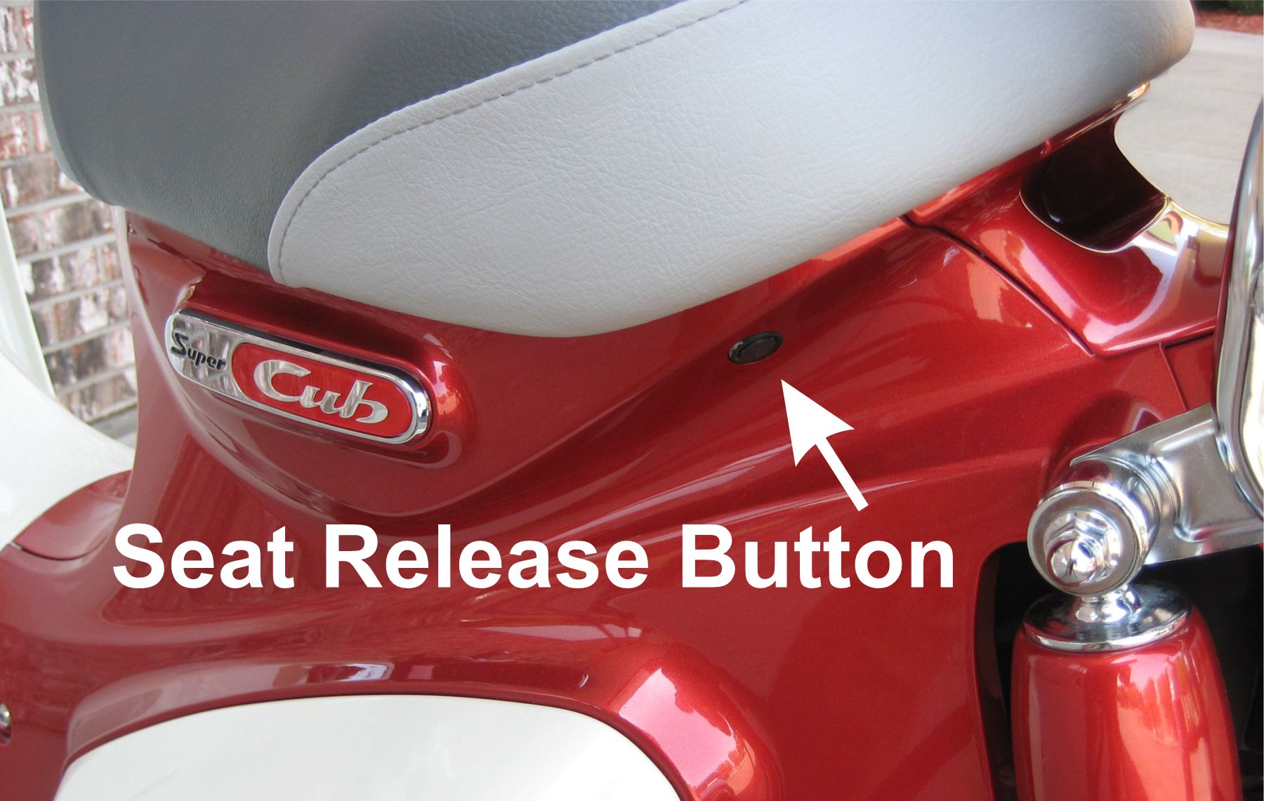 Seat release button underneath Super Cub seat