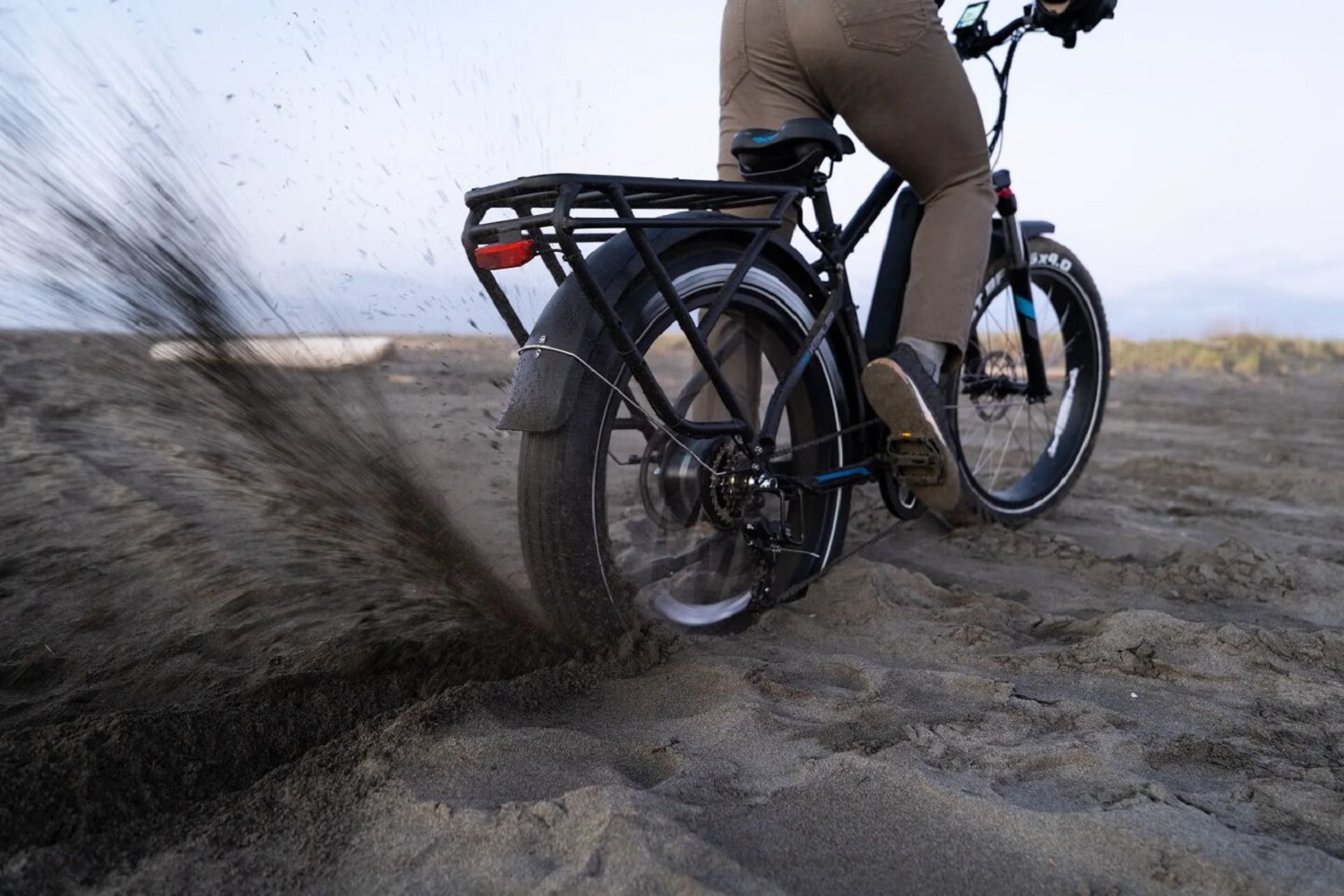 Rear heavy fat-tire electric bike kicks up sand from burnout on beach