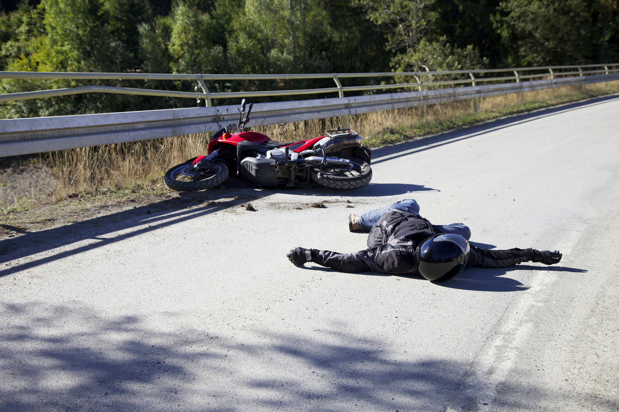 motorcycle rider lies next to their bike on the road after a colission