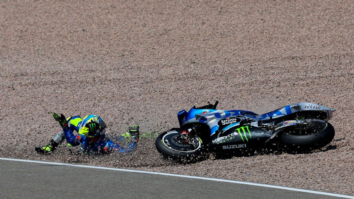 MotoGP rider comes off his motorcycle and slides into the gravel during a race