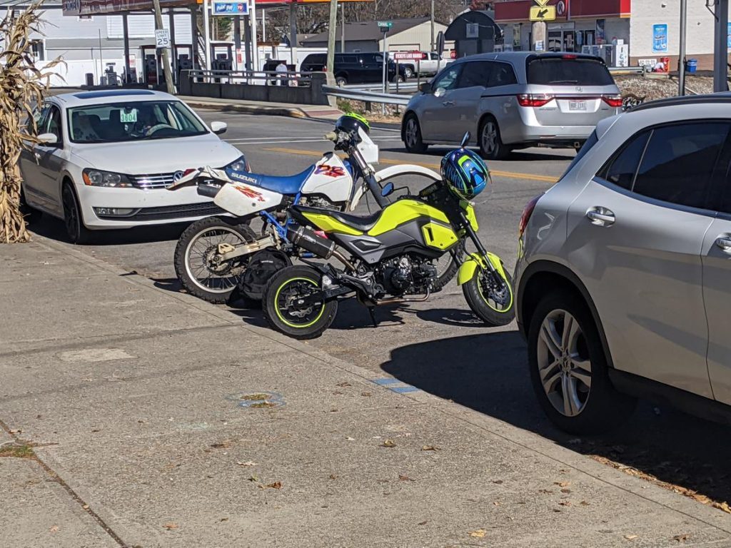 Suzuki DR400 and Honda GROM parked at the base of hill