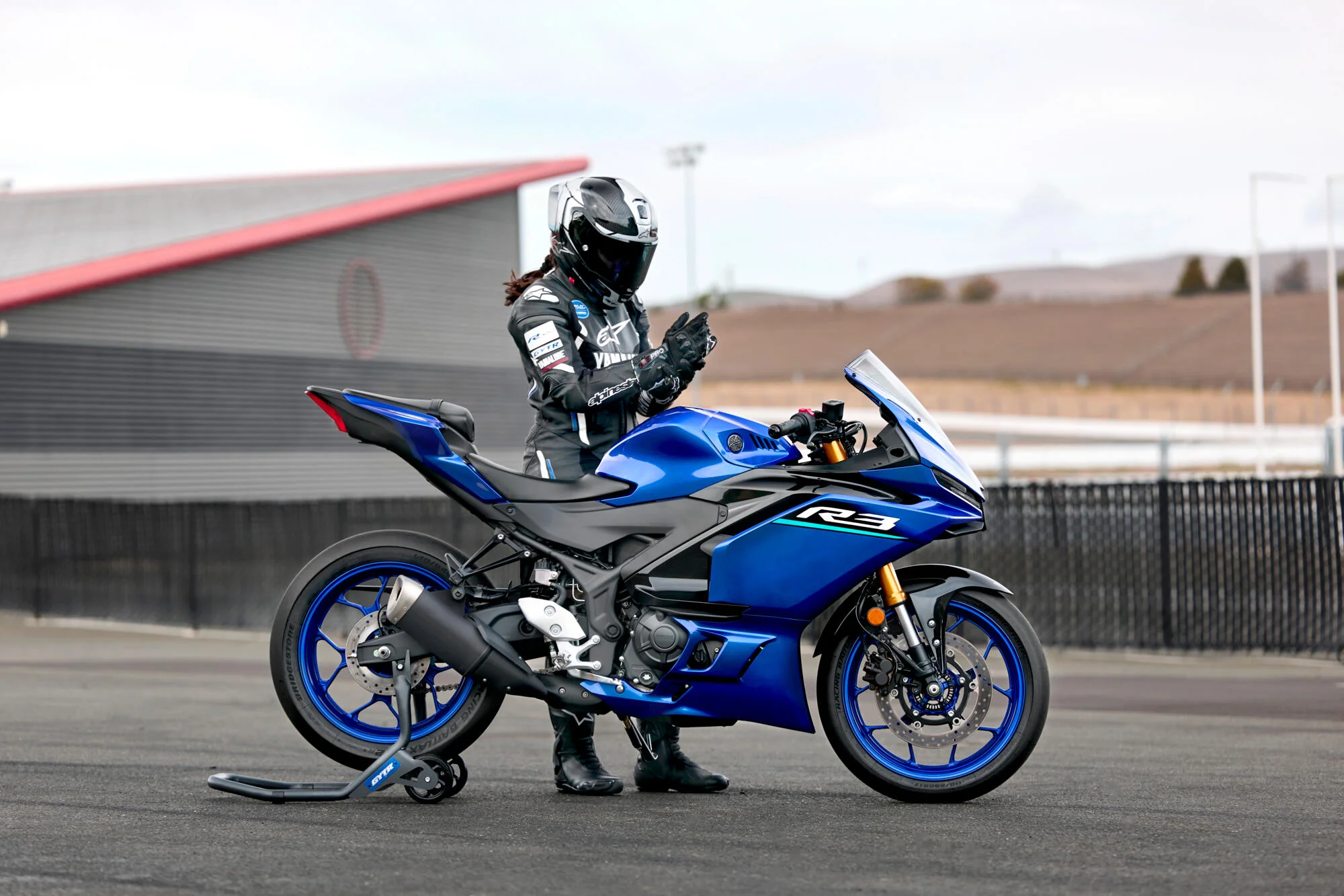 Side view of a Yamaha R3 bike and rider at racetrack