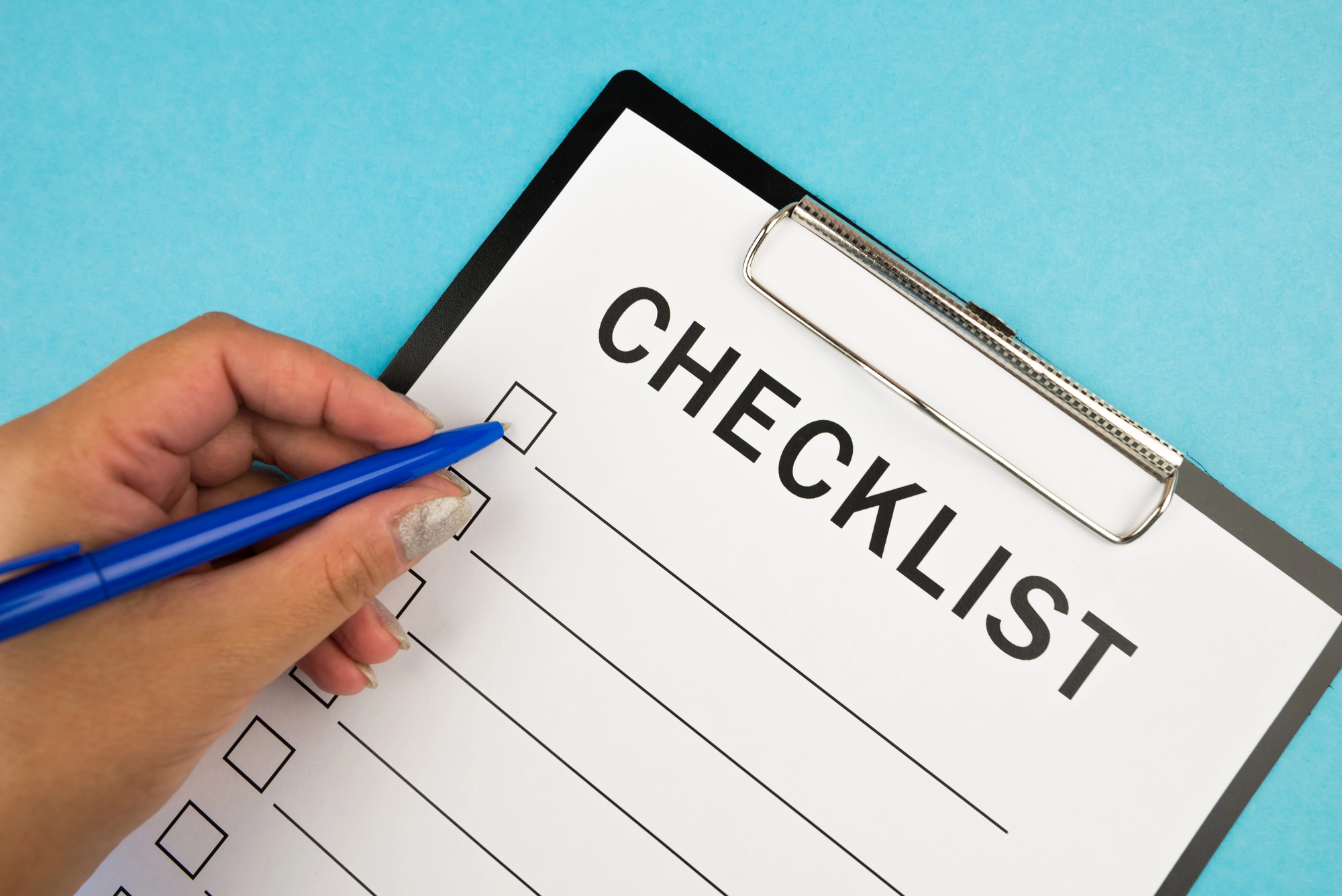 Person checking off items on a clipboard checklist with a blue pen